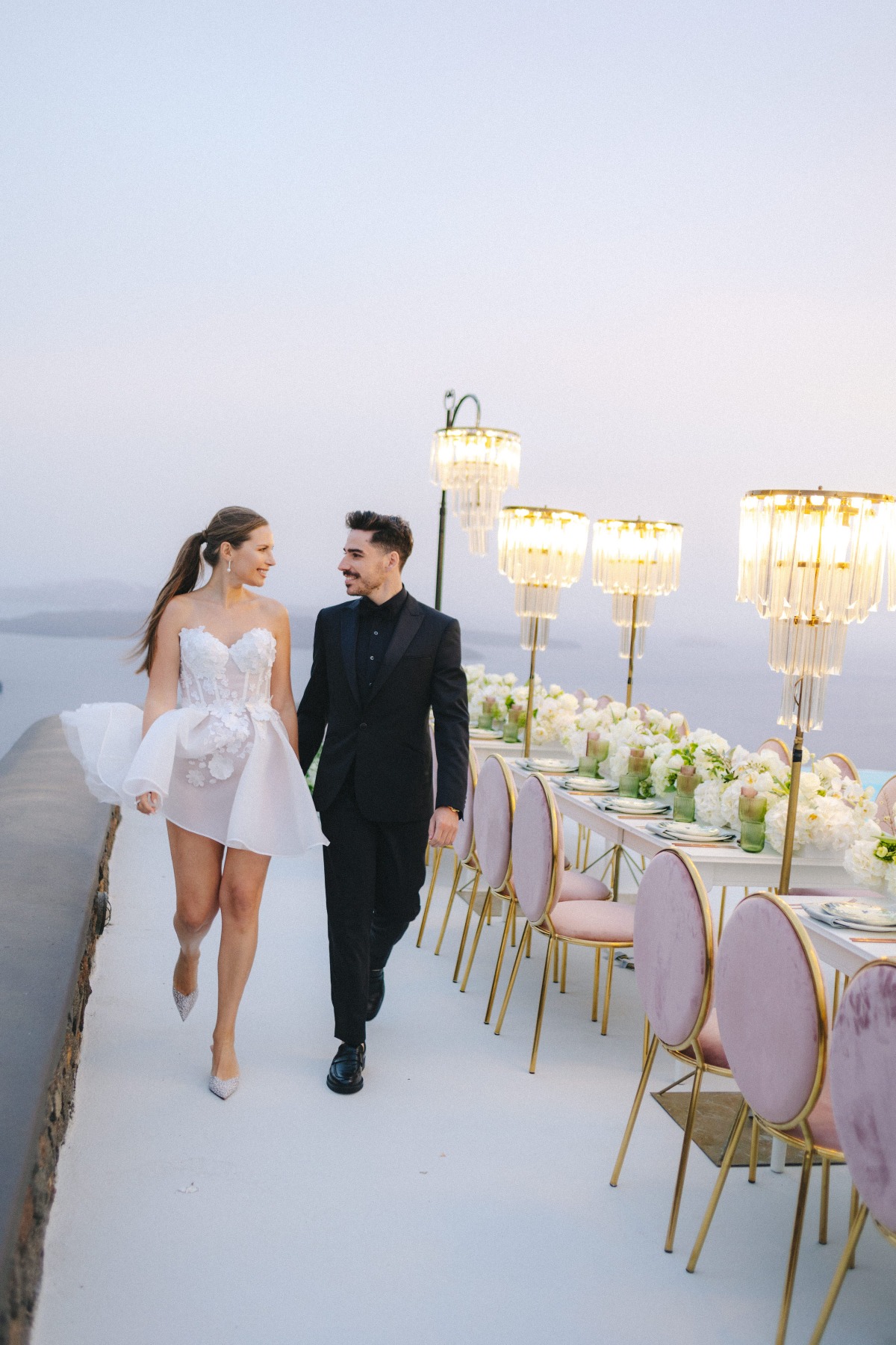 bride and groom walking at seaside reception in santorini