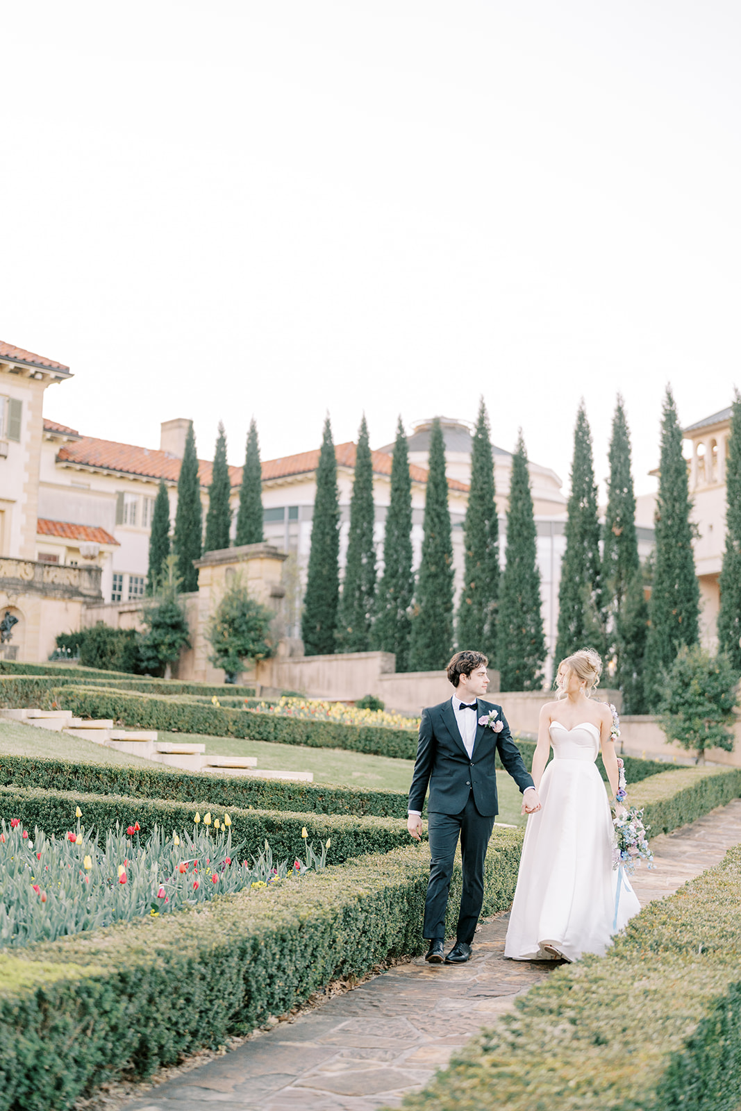 bride and groom walking through italian inspired garden