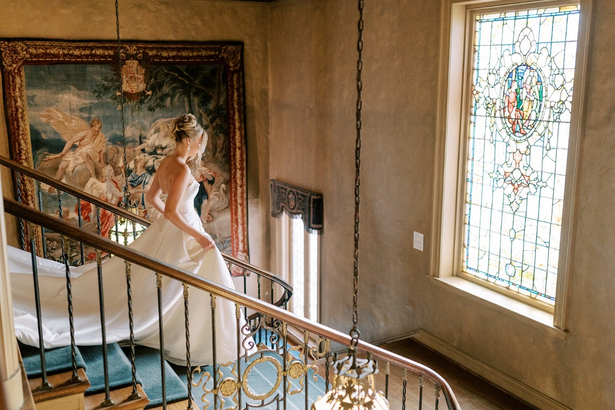 bride walking down stairs at estate with stained glass