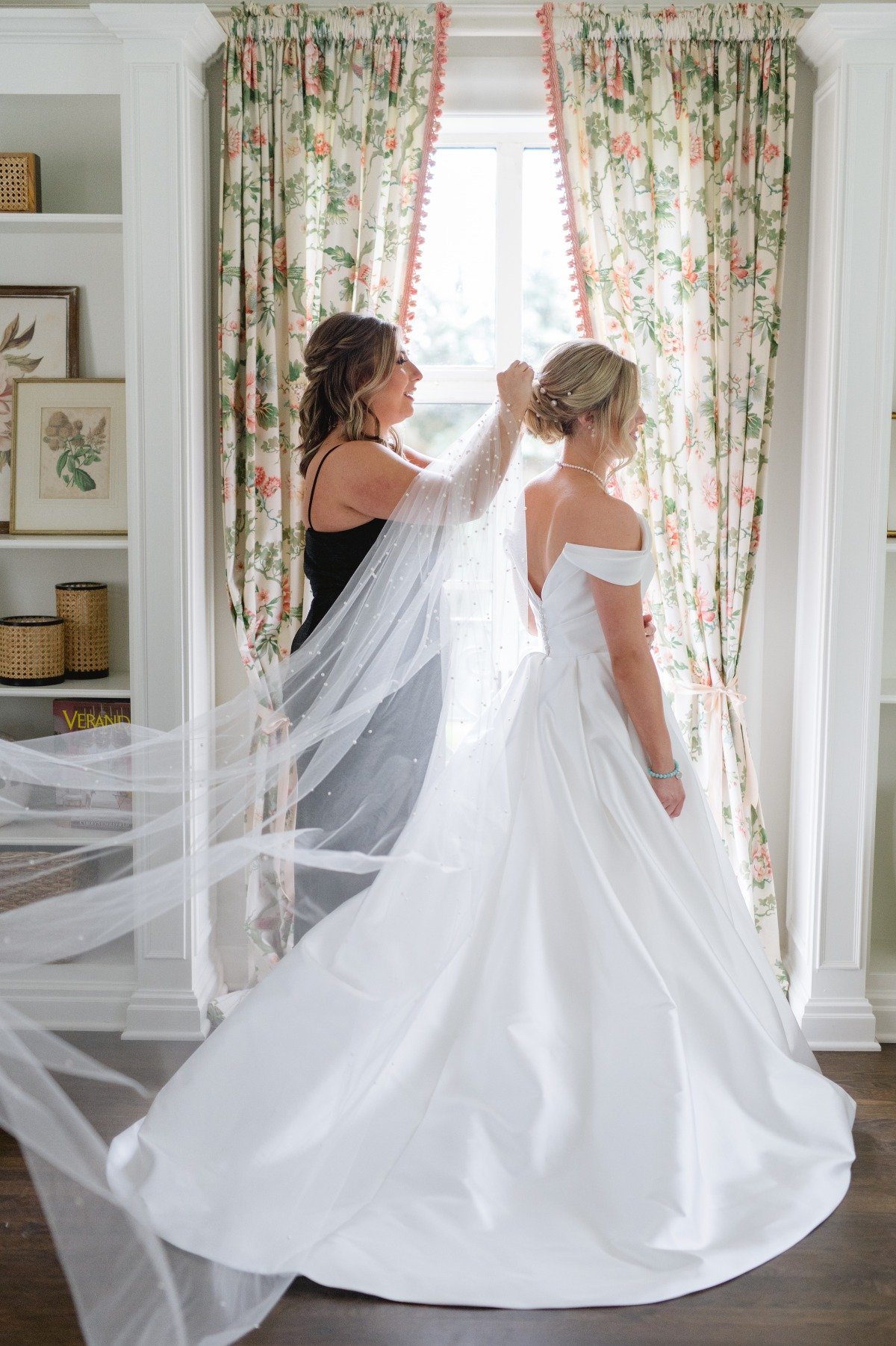 bridesmaid helps bride put on veil