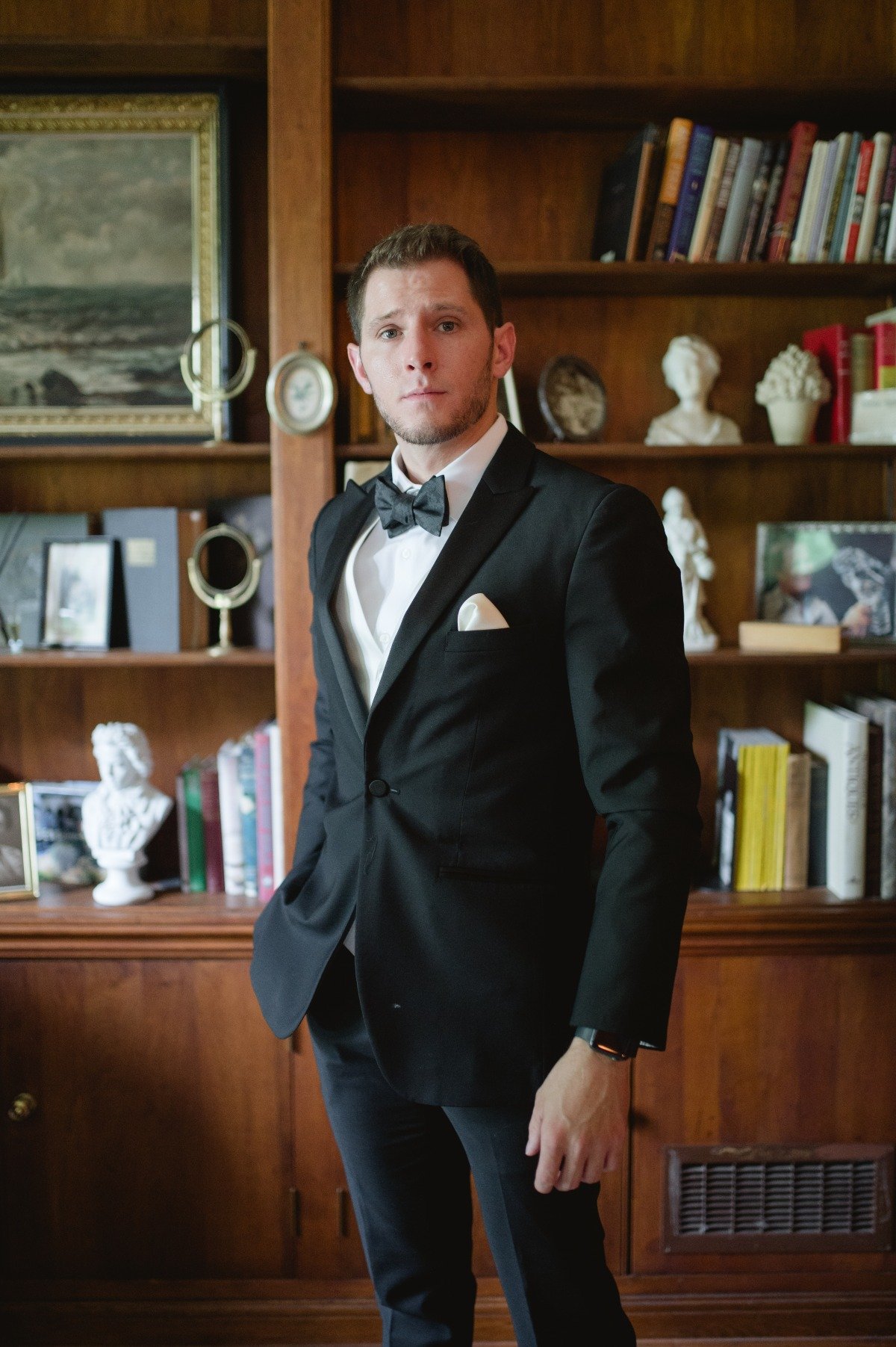 groom in black tuxedo in library