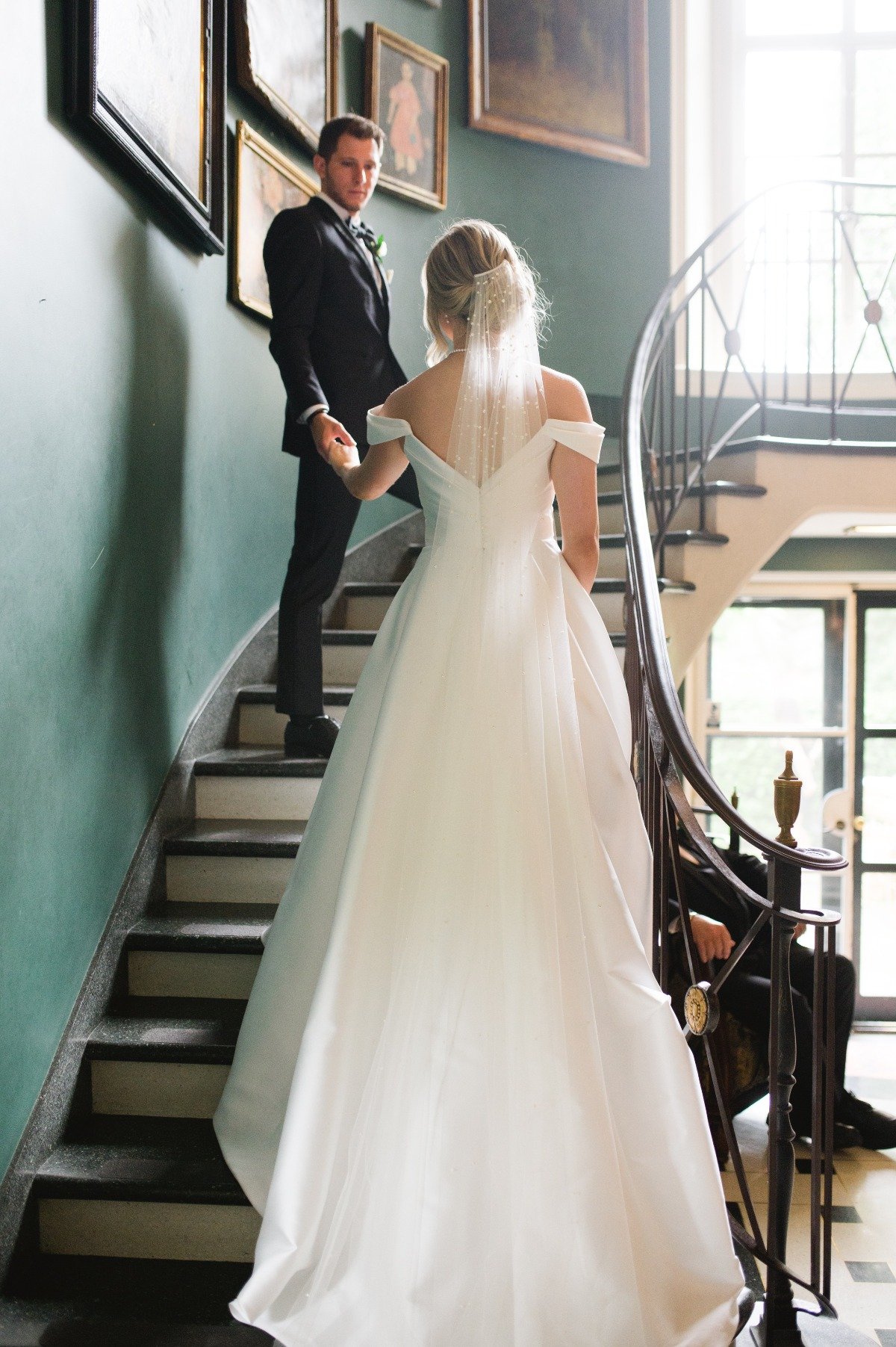 bride and groom walking up staircase at manor