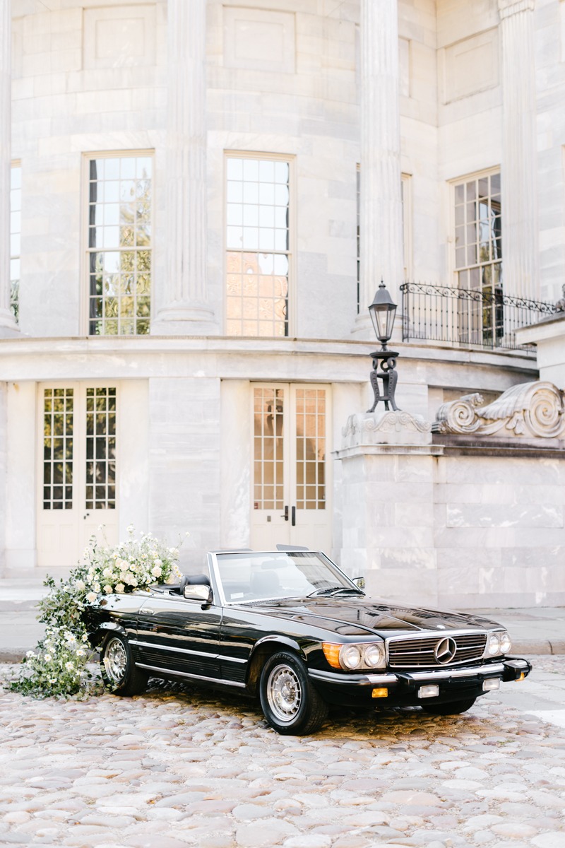 black vintage getaway car for wedding with wildflower installation