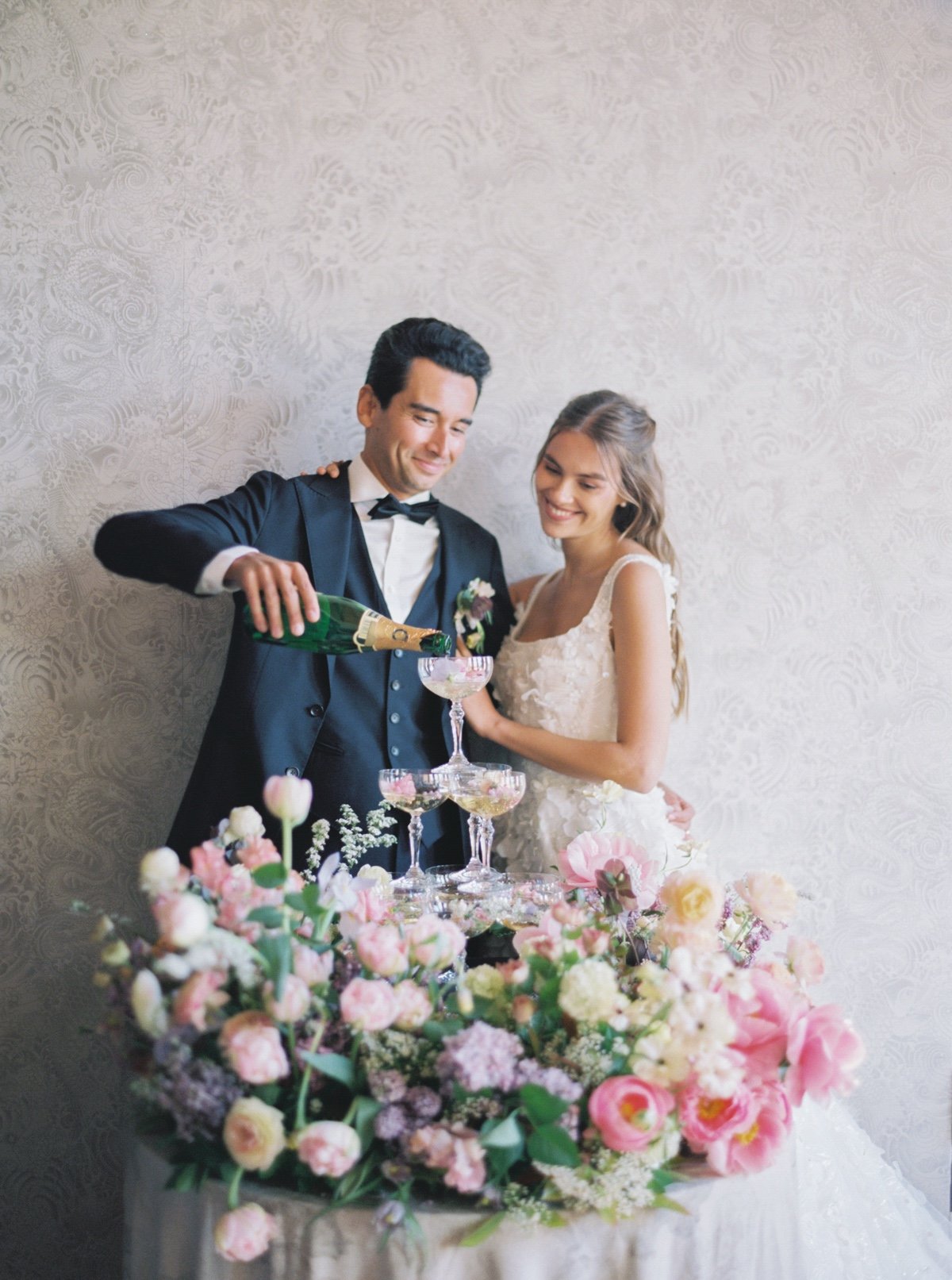 bride and groom pouring a champagne tower at pastel colored wedding