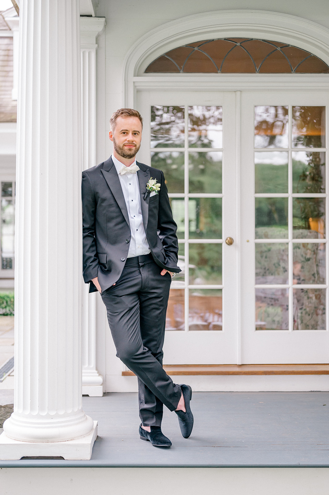 groom at estate in black tuxedo with velvet loafers