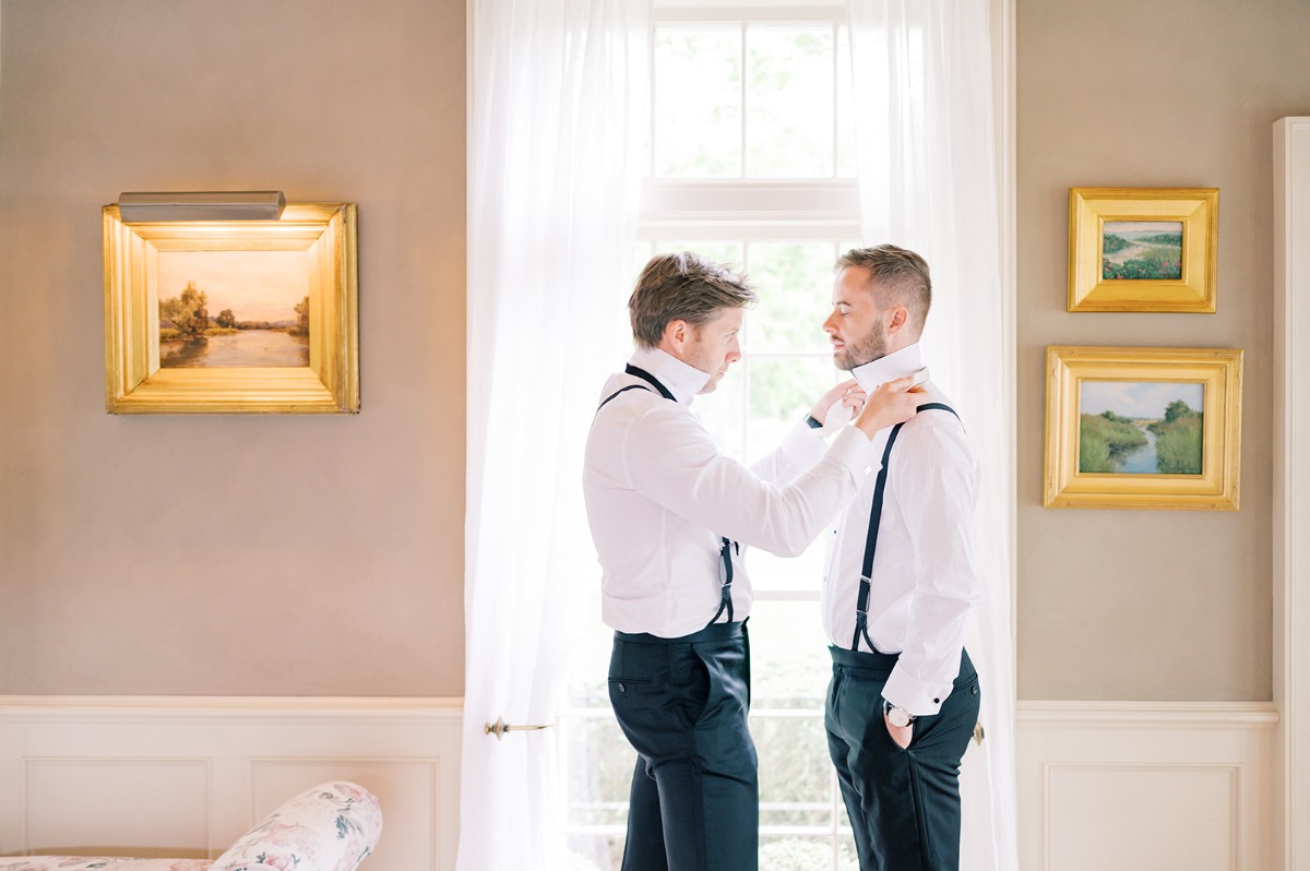 groomsman helping groom tie bow tie