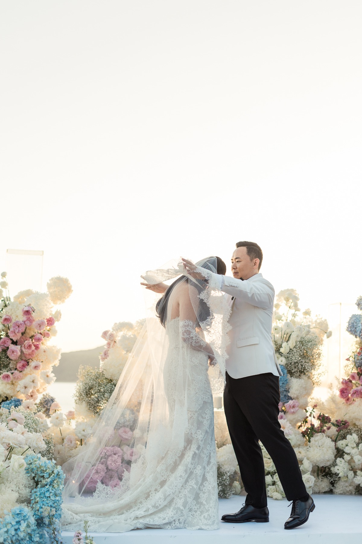 groom lifts veil at outdoor pastel themed wedding