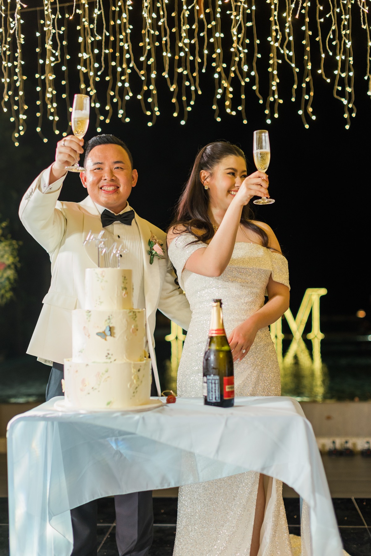 bride and groom toast under twinkle lights