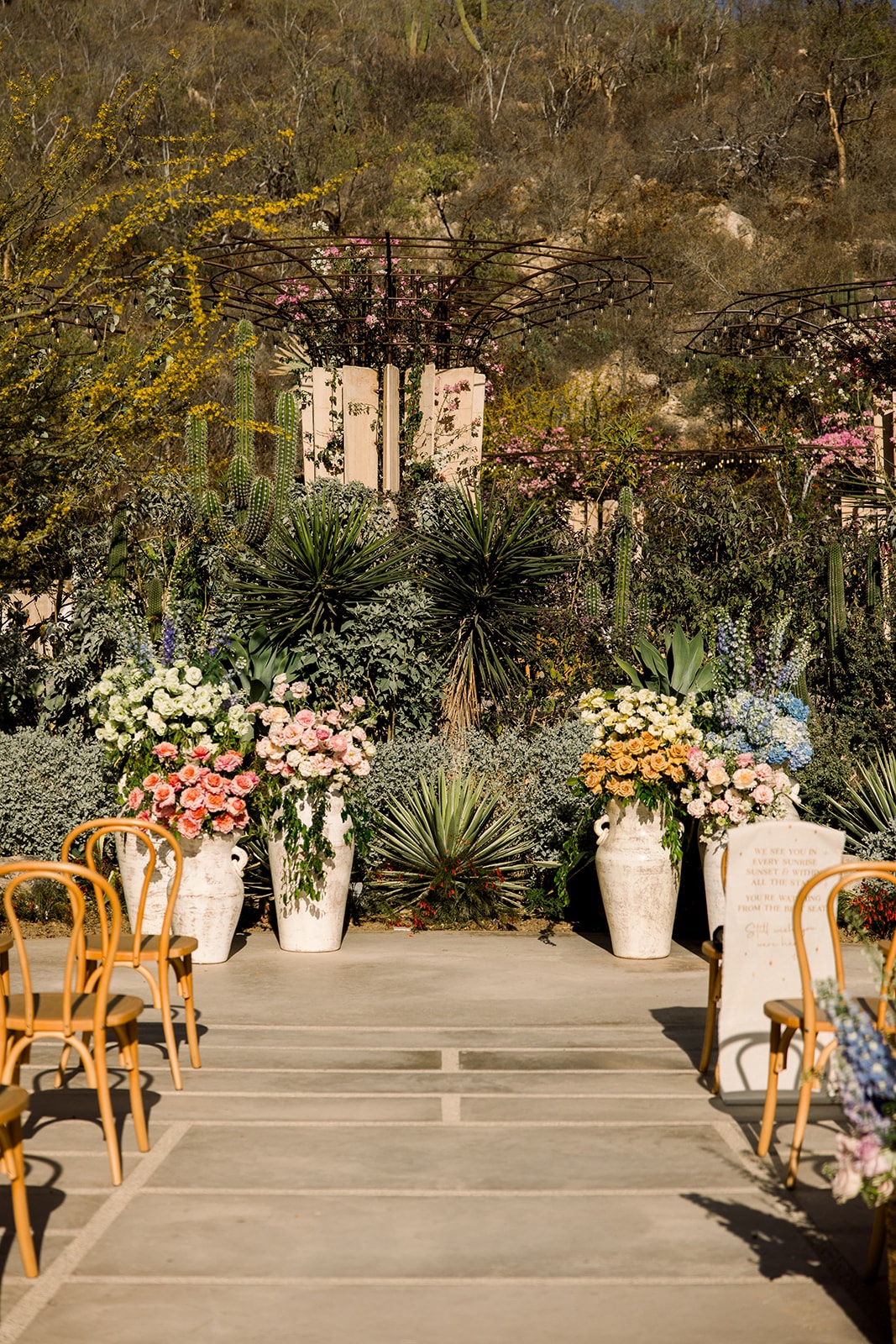 altar of muted rainbow flowers in tall white vases