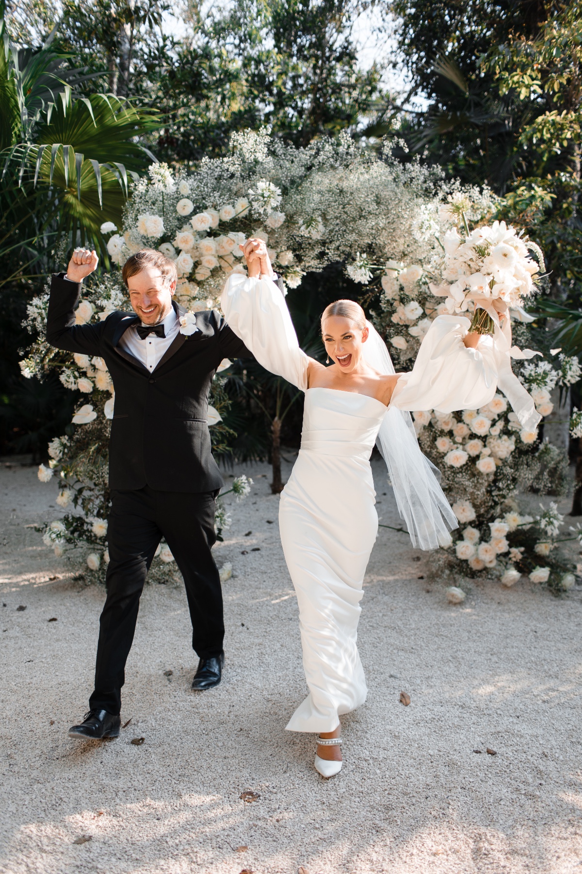 bride and groom elope with peach and white floral arch