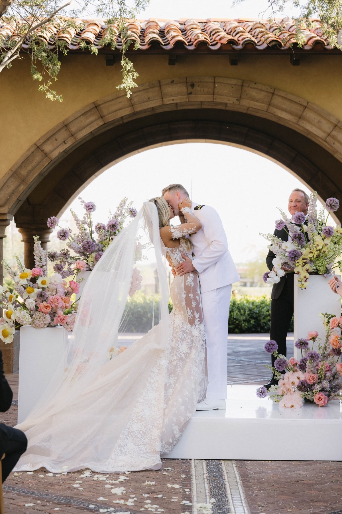 bride and groom kiss at pastel colored garden wedding ceremony