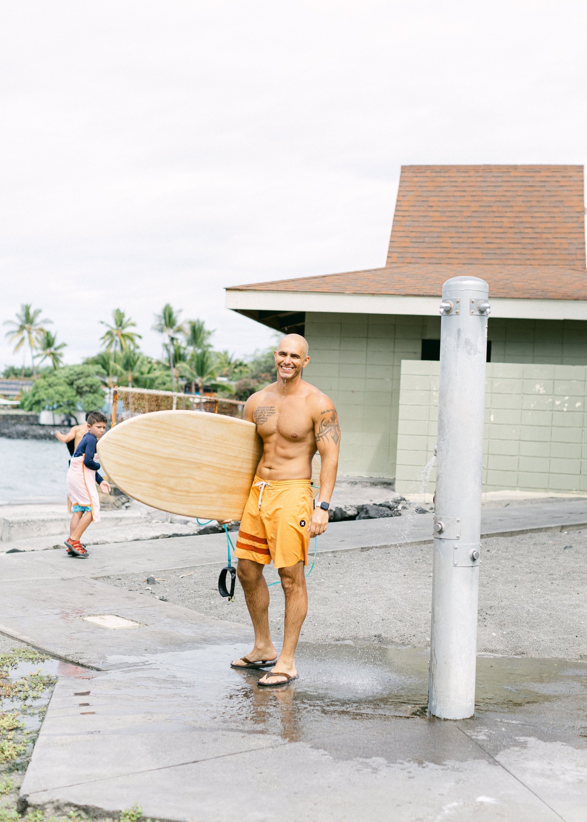 groom with surfboard on wedding day in hawaii