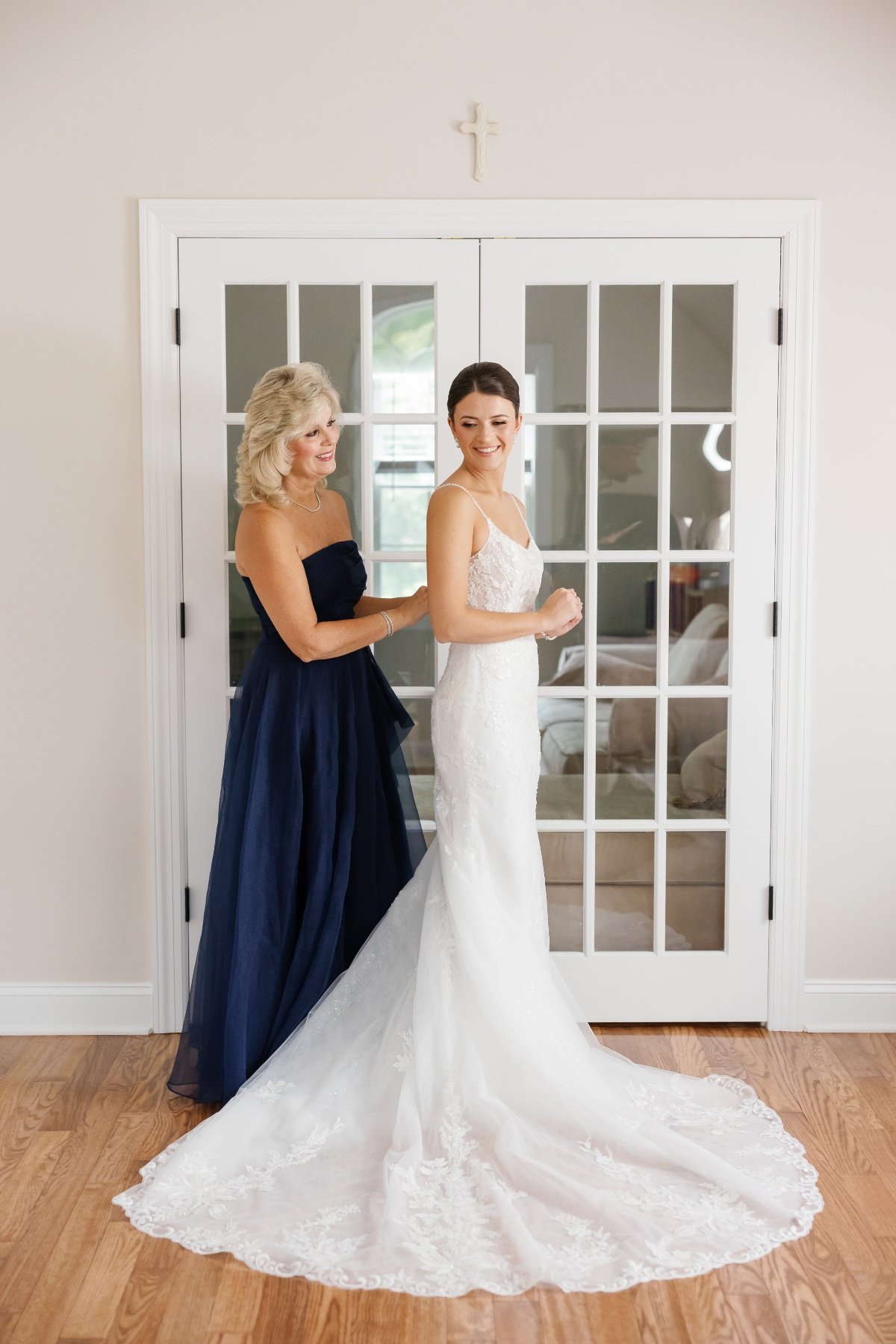 mom zipping dress for daughter getting ready for wedding