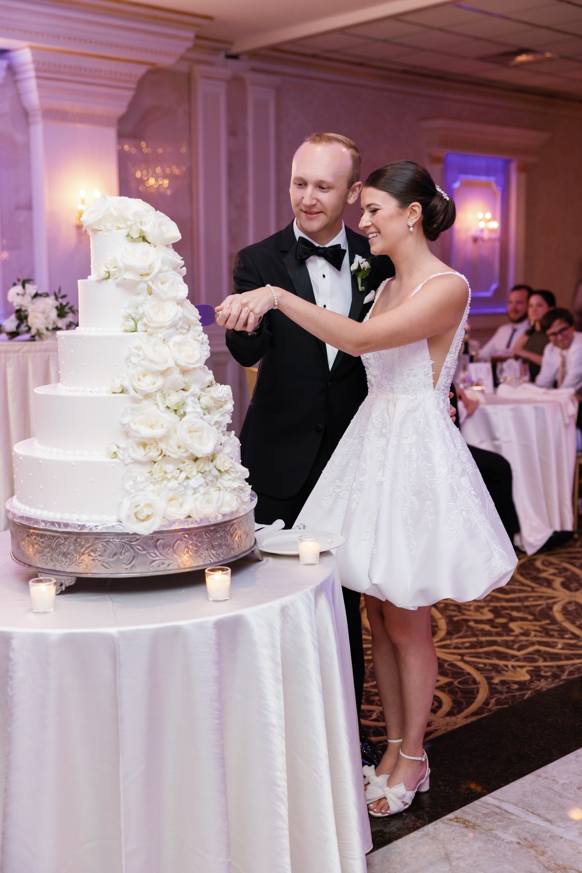 bride in mini dress cutting cake at wedding reception