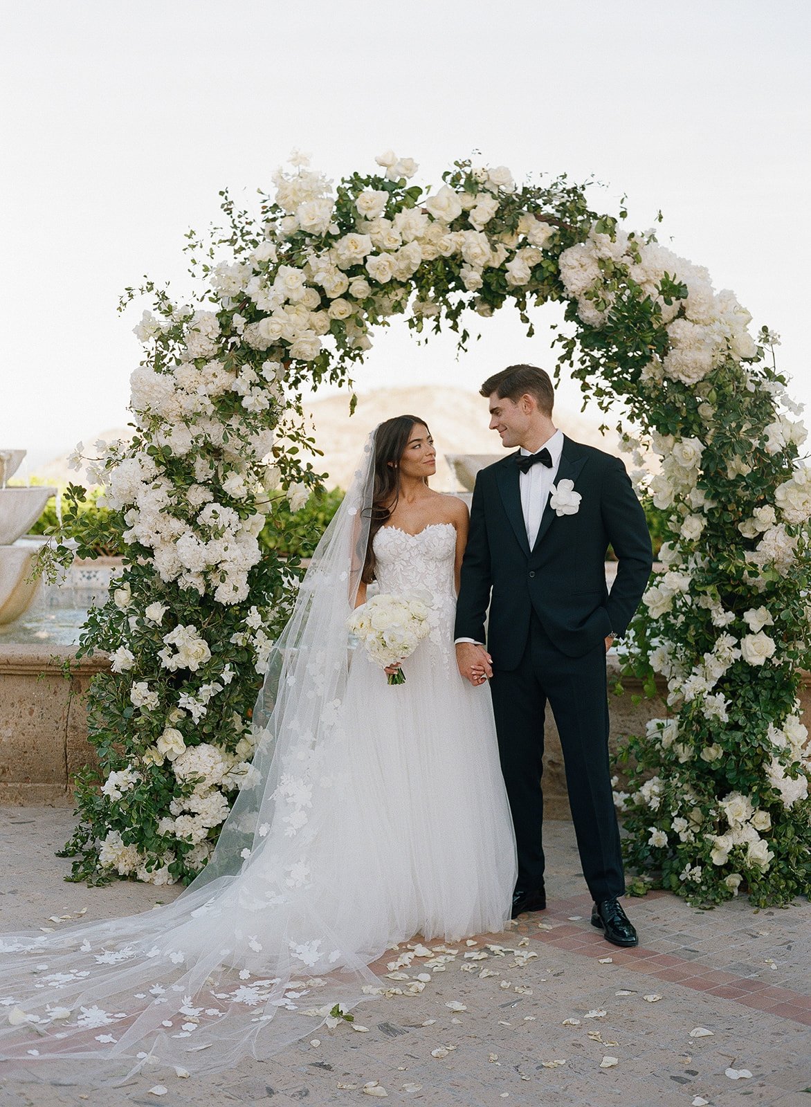 bride and groom at black-tie wedding with rose arch