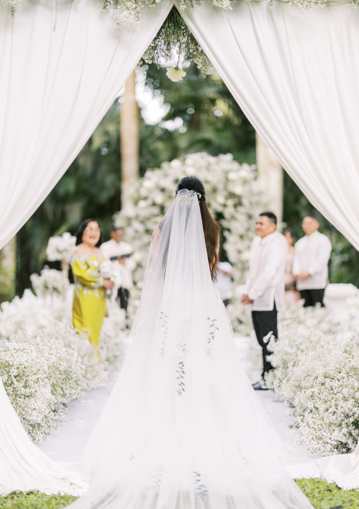 bride walking down white aisle with drapery