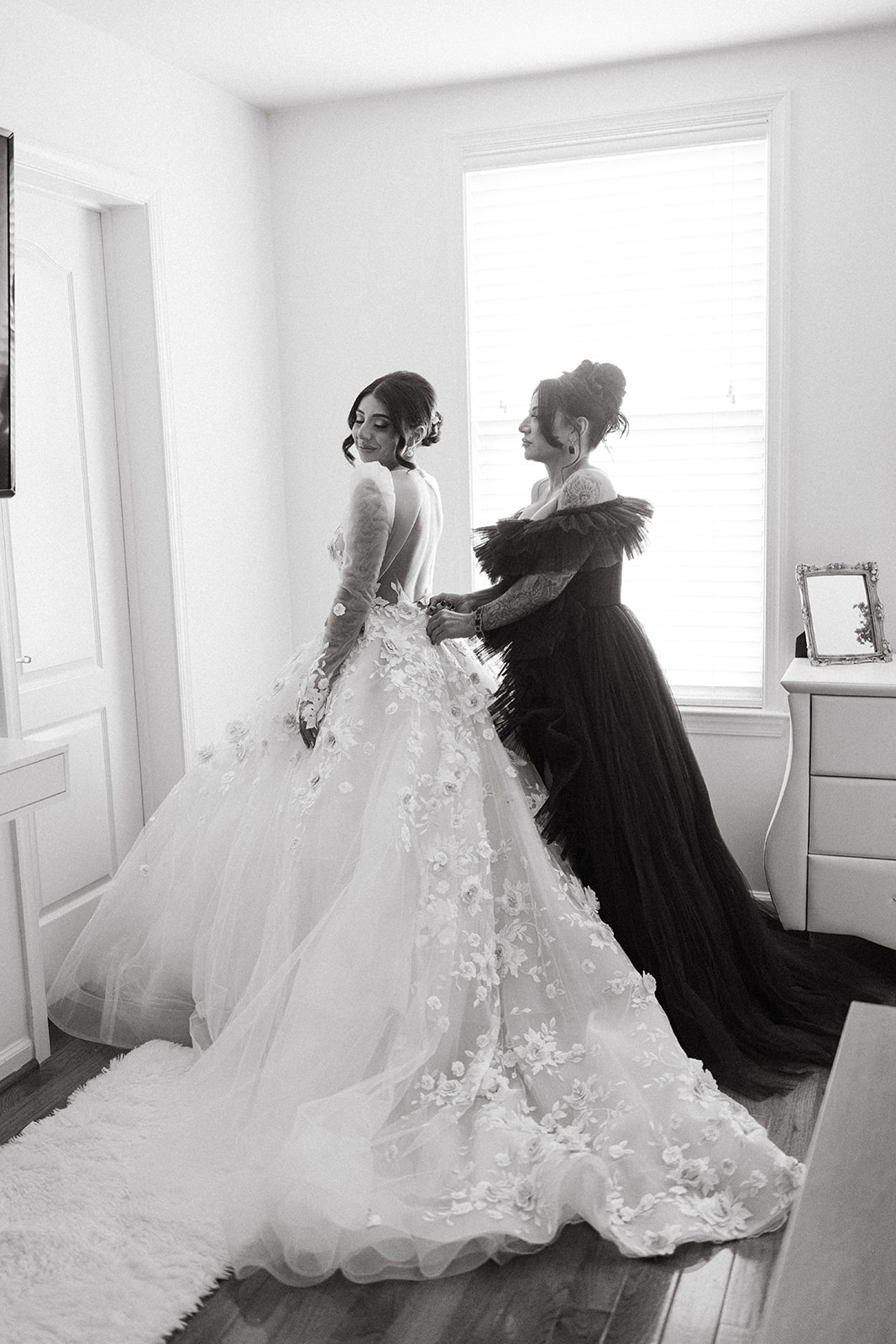 mother of the bride in feathered dress zipping up bride