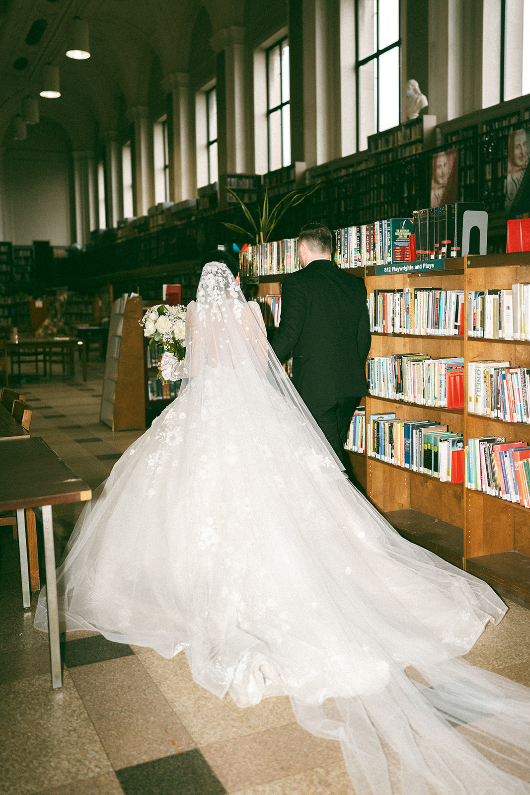 bride and groom walking through library at wedding