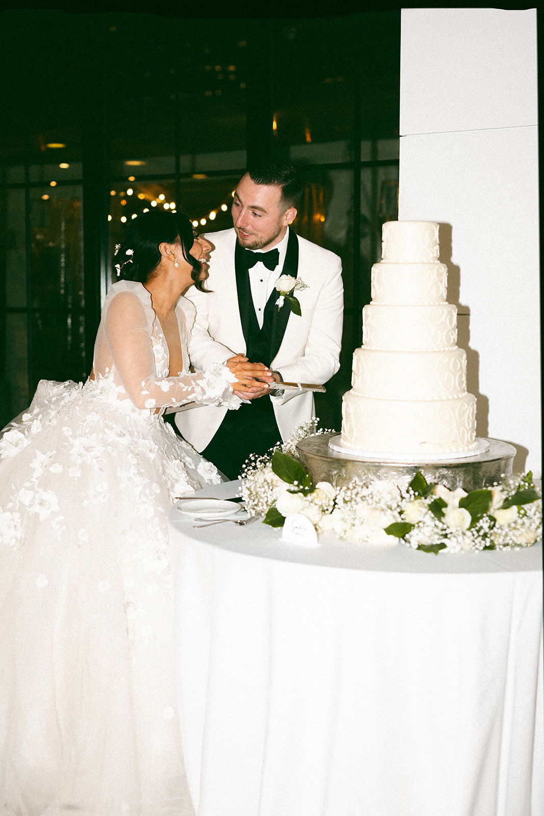 bride and groom cutting all white wedding cake