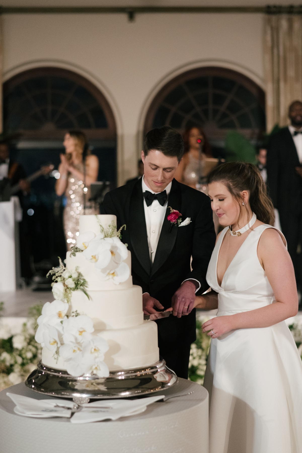 bride and groom cut white fondant wedding cake with orchids