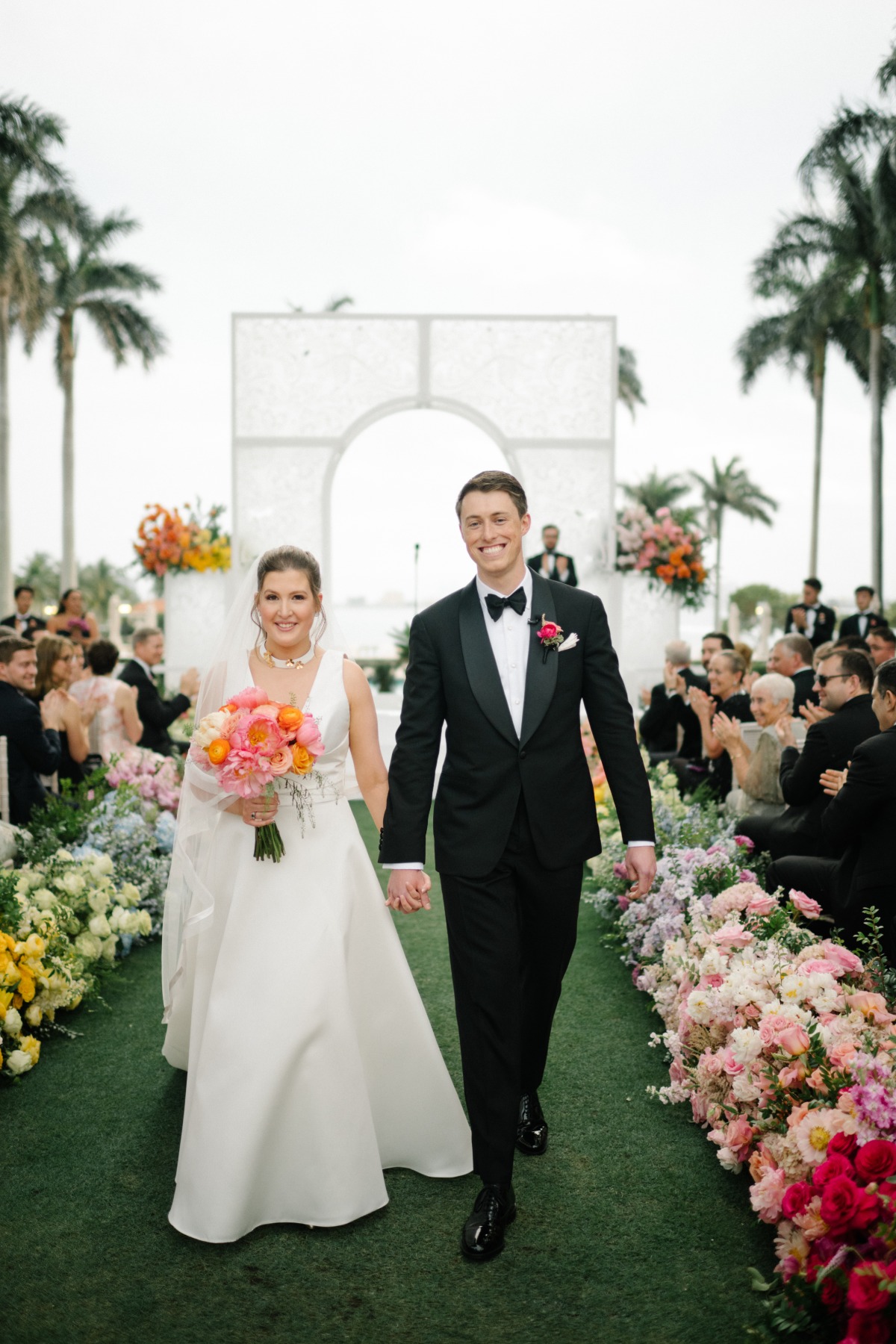 bride and groom walking down the aisle at rainbow wedding ceremony