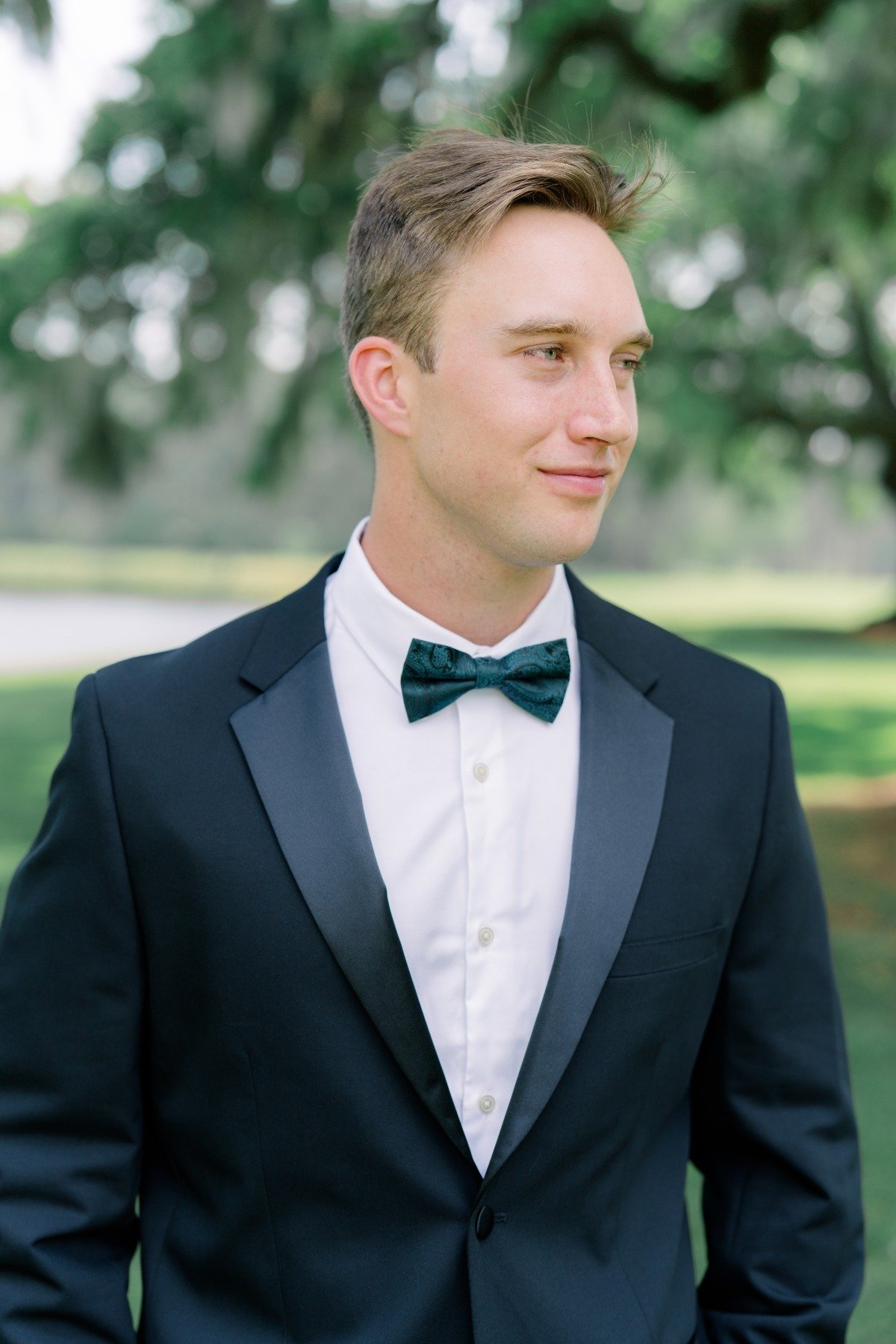 groom in black tuxedo with printed green bowtie