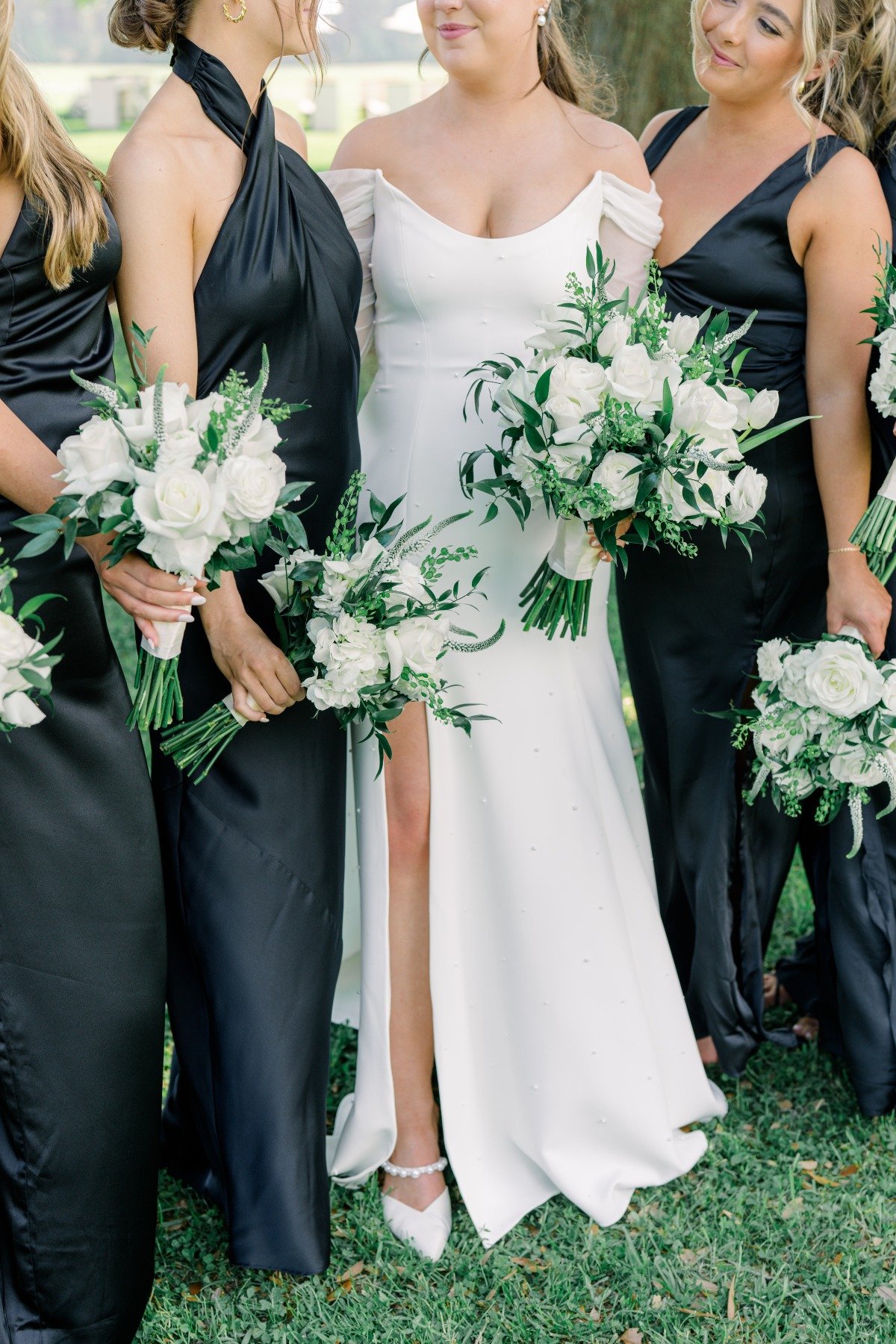 bride in long sleeve gown with bridesmaids in mix and match black dresses