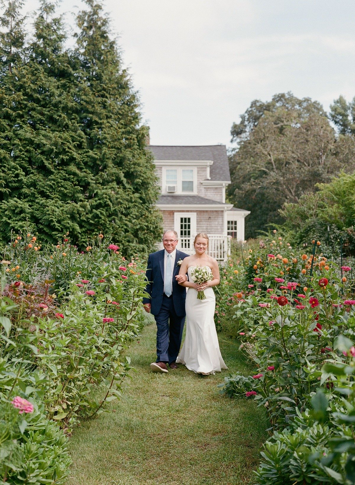 father of the bride walking her down the aisle with wildflowers