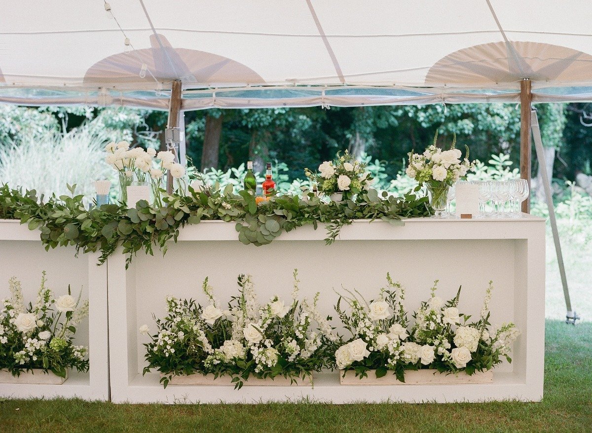 white flowers on portable outdoor bar at tented reception