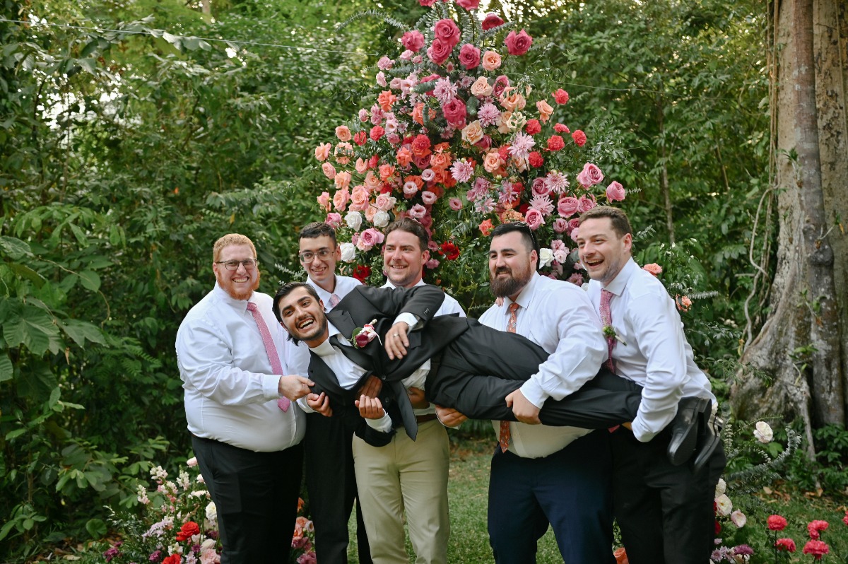 Silly groomsmen in front of flowers