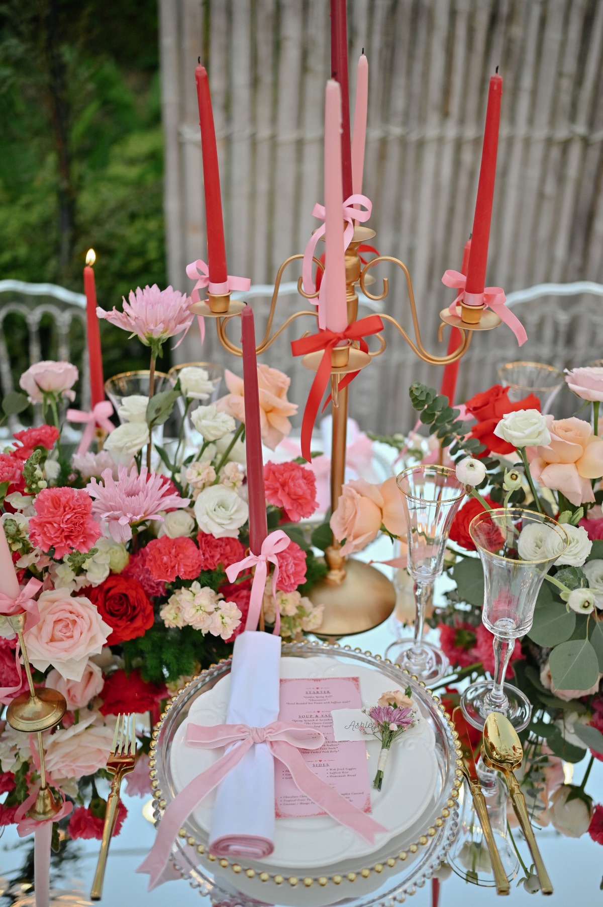 pink and red place setting with gold silverware and pink bows