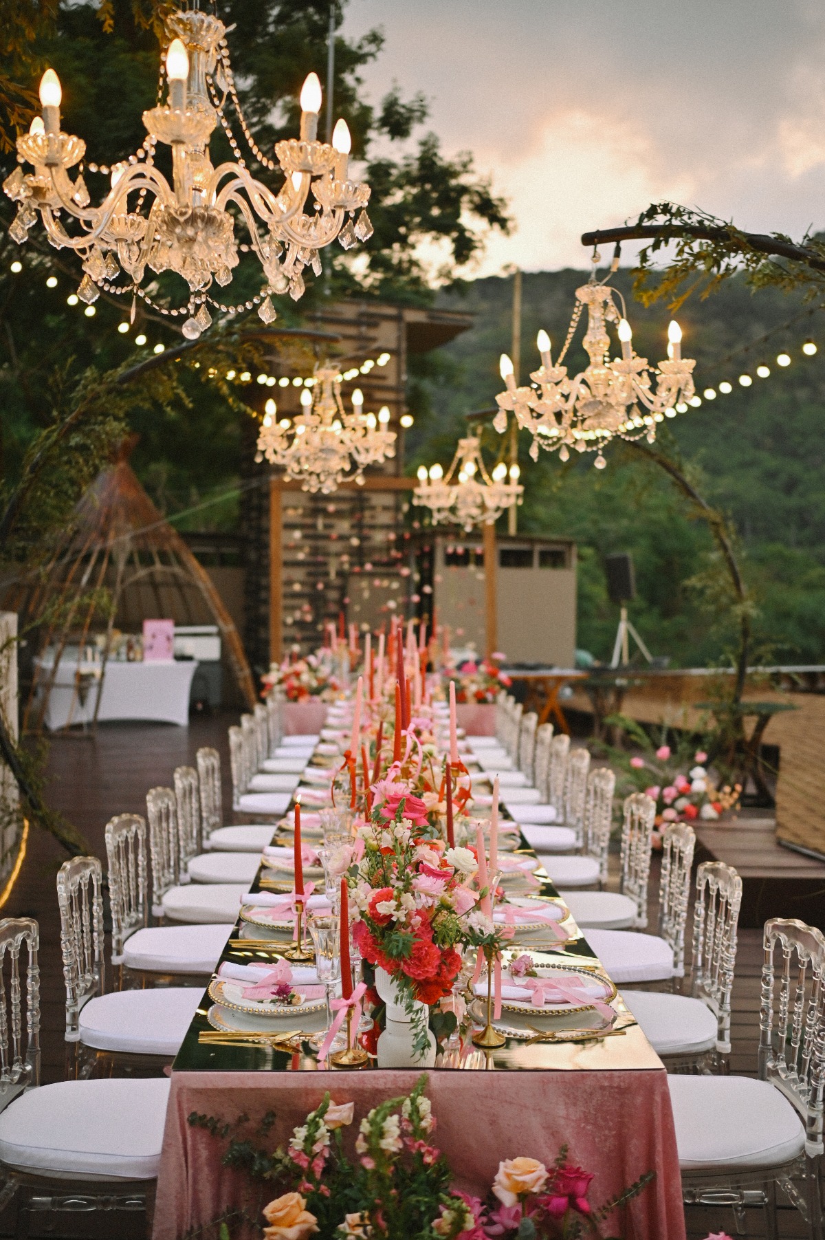 reception set up under hanging chandeliers and a table decorated with pink and reds