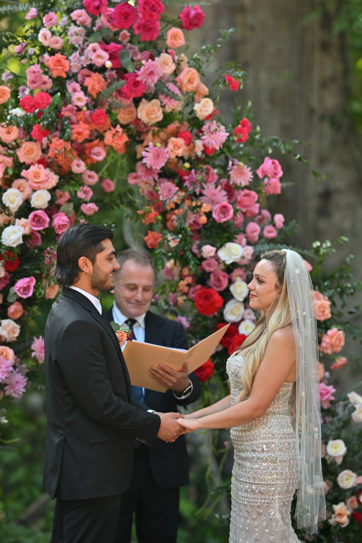 pink and orange wedding ceremony with officiant speaking to couple