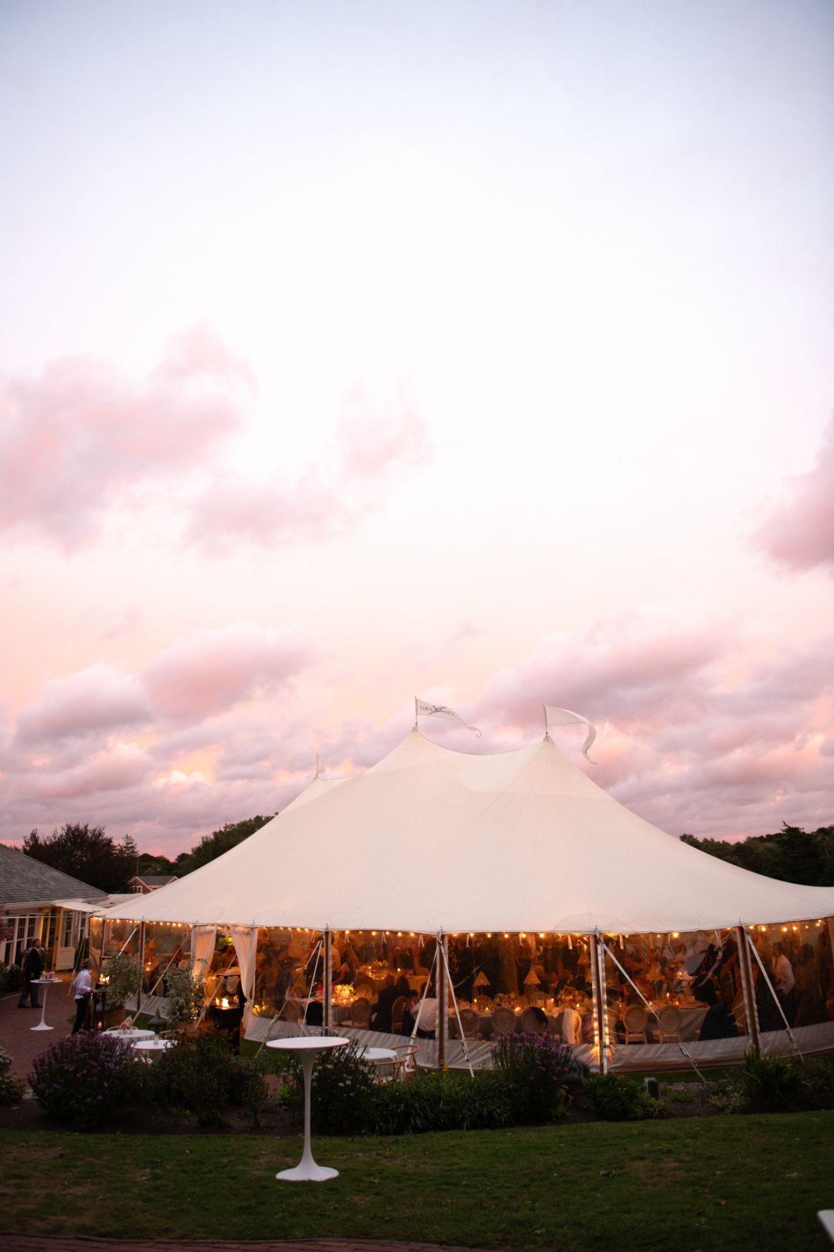 a white tented wedding reception with a pink sky