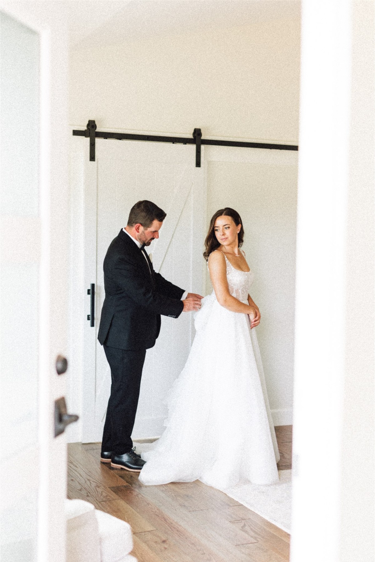 groom zipping up brides gown