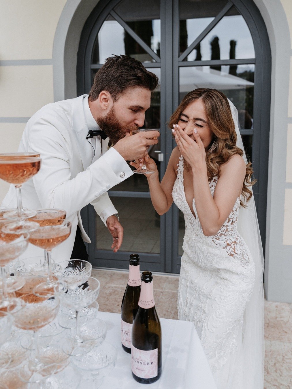 bride and groom pour pink champagne tower for wedding