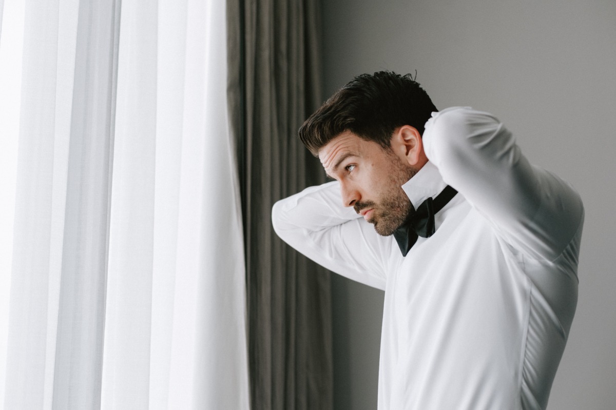 groom putting on his bowtie for wedding