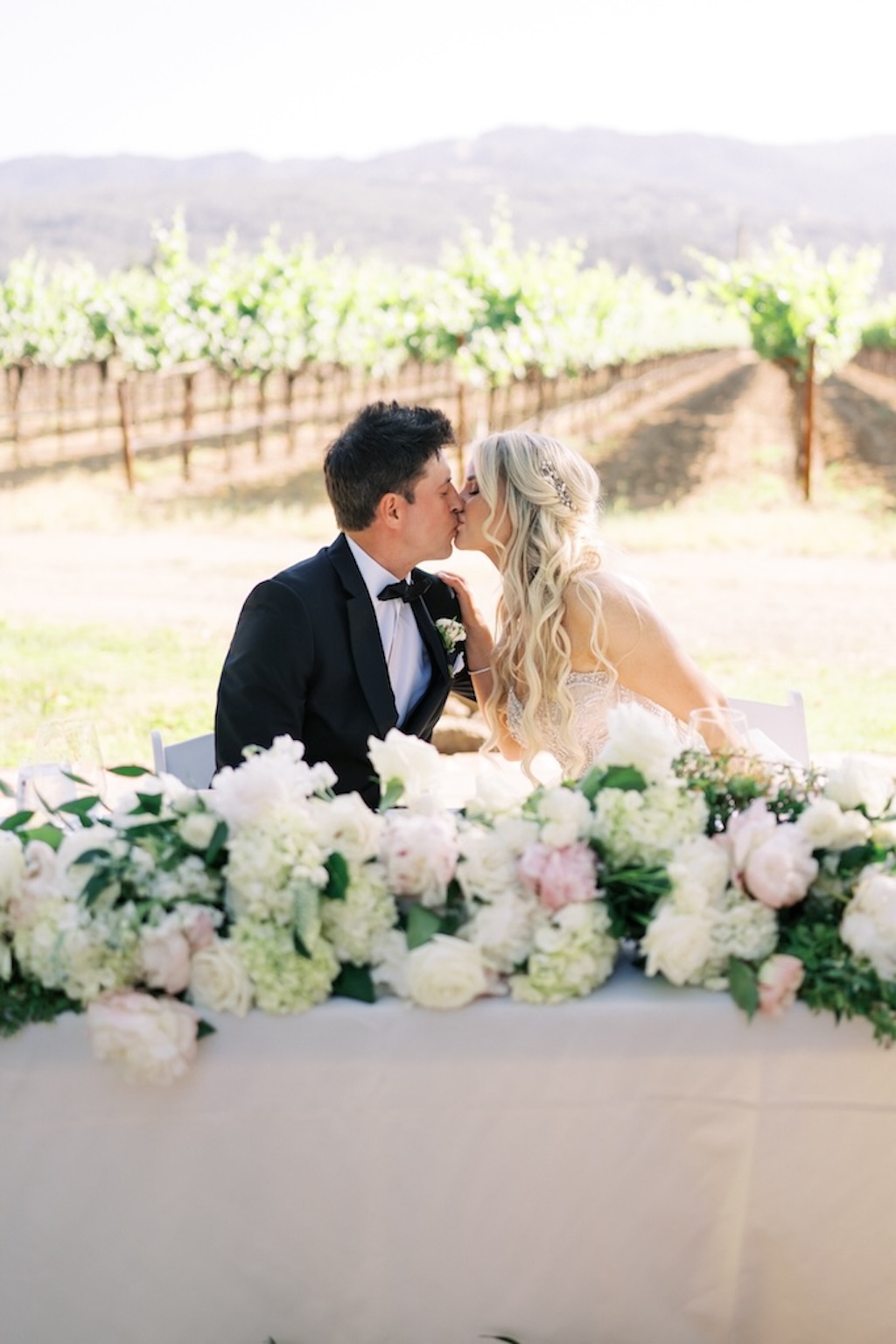 bride and groom at sweetheart table at blush vineyard wedding