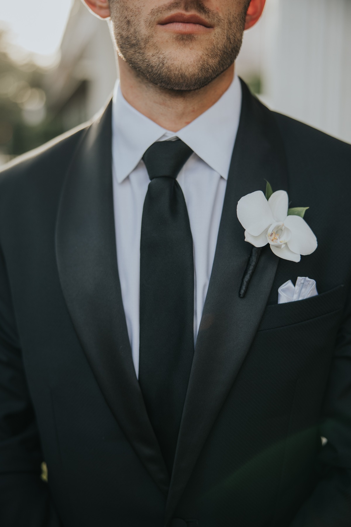 groom in black tuxedo with white orchid boutonnière 