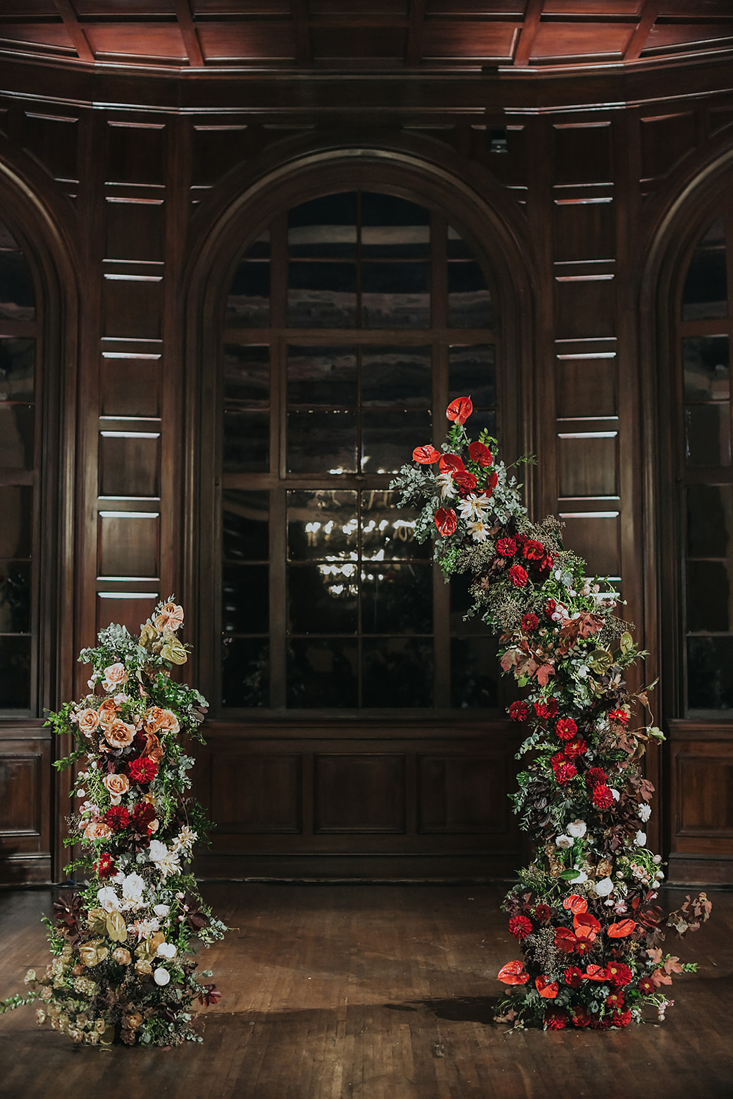 red and mauve abstract floral arch at indoor wedding