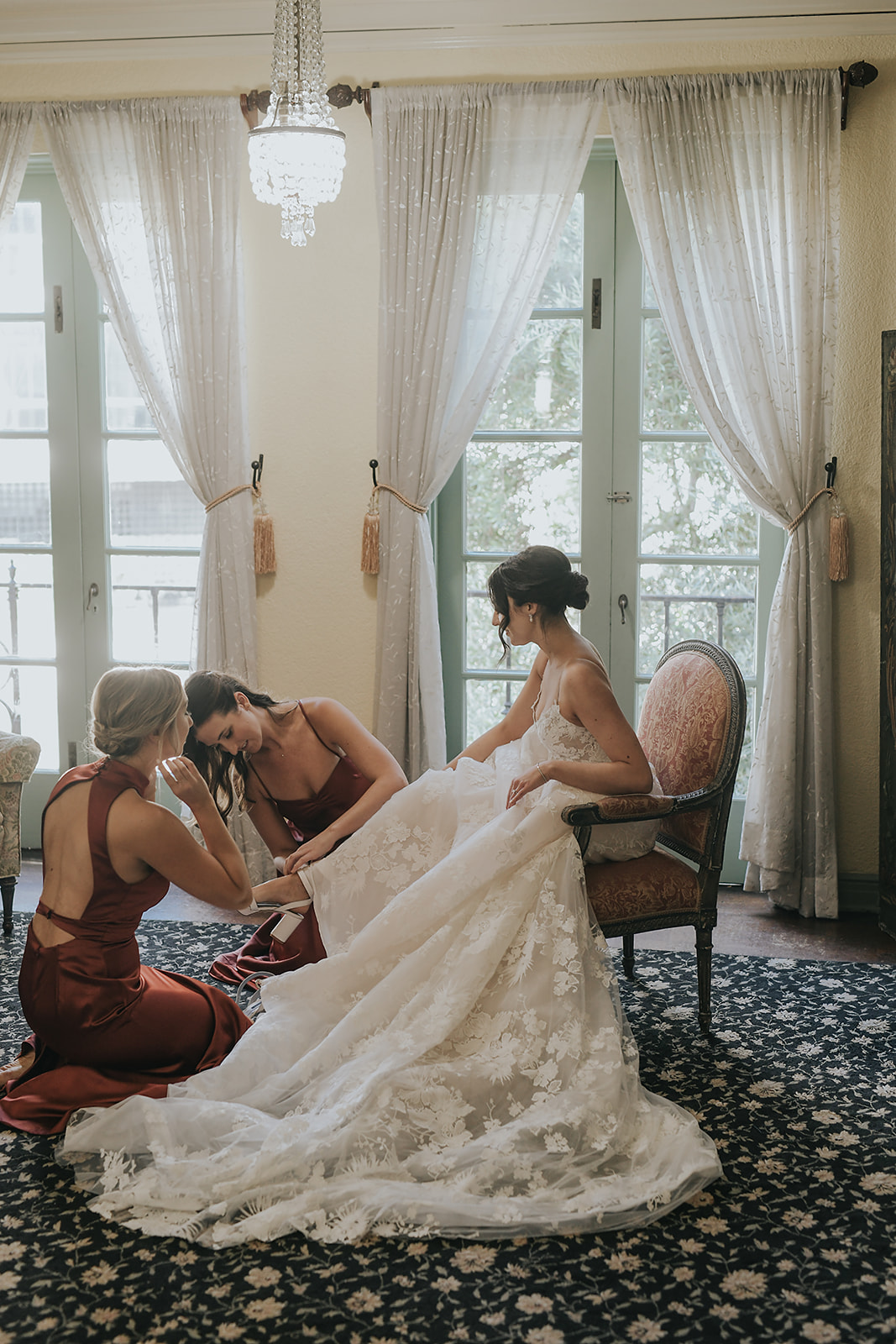 bridesmaids helping bride put her shoes on