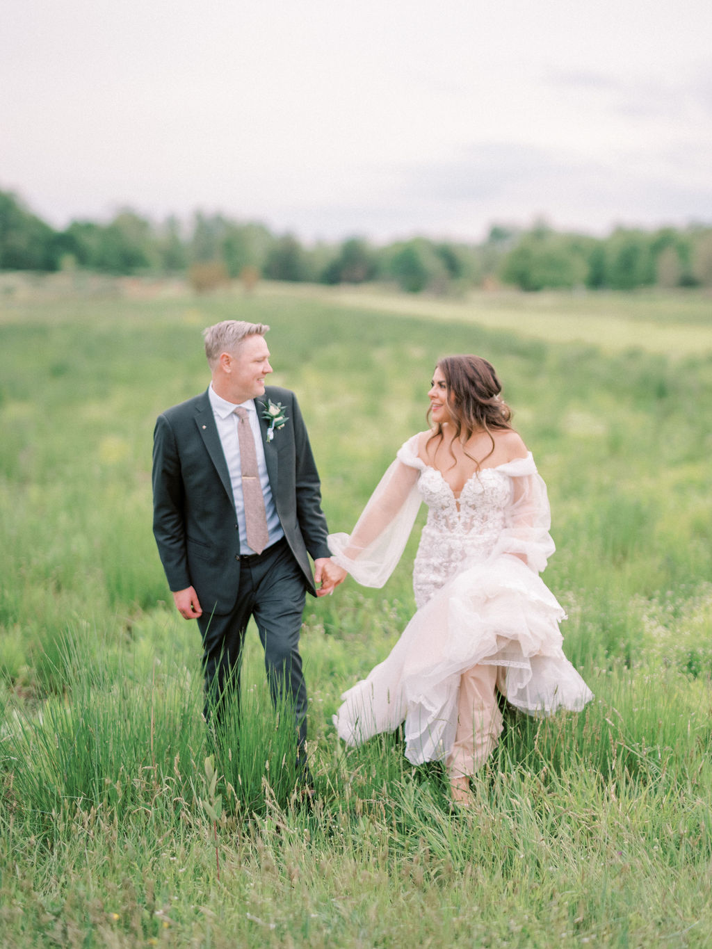 bride and groom walking through field in virginia wedding venue