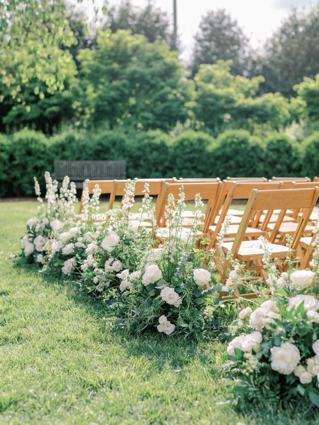 white rose arrangements lining the aisle for wedding ceremony