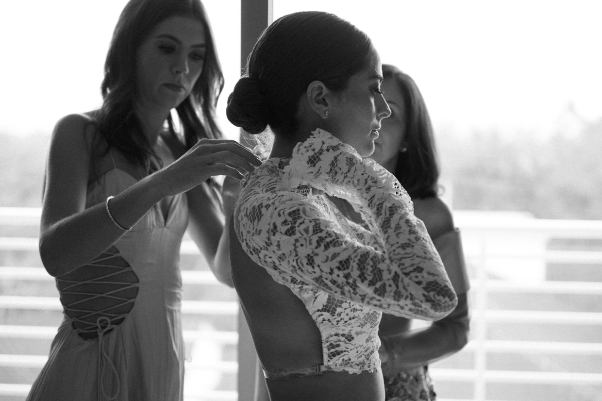 bridesmaids helping bride into galia lahav lace top