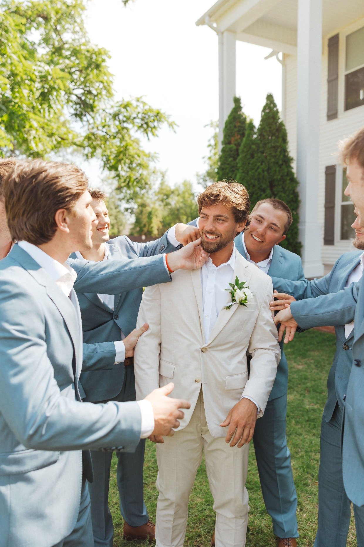 groom in tan with groomsmen in blue by with great love