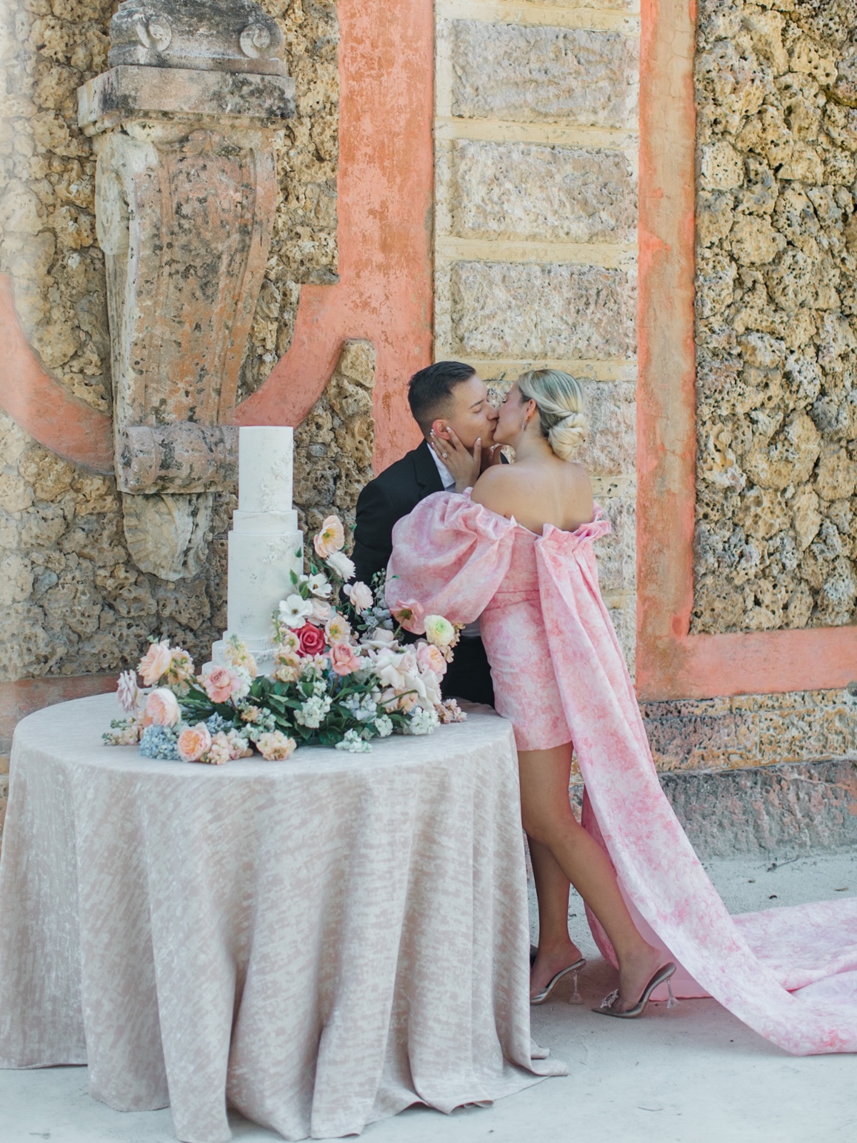 couple kiss by wedding cake photo idea