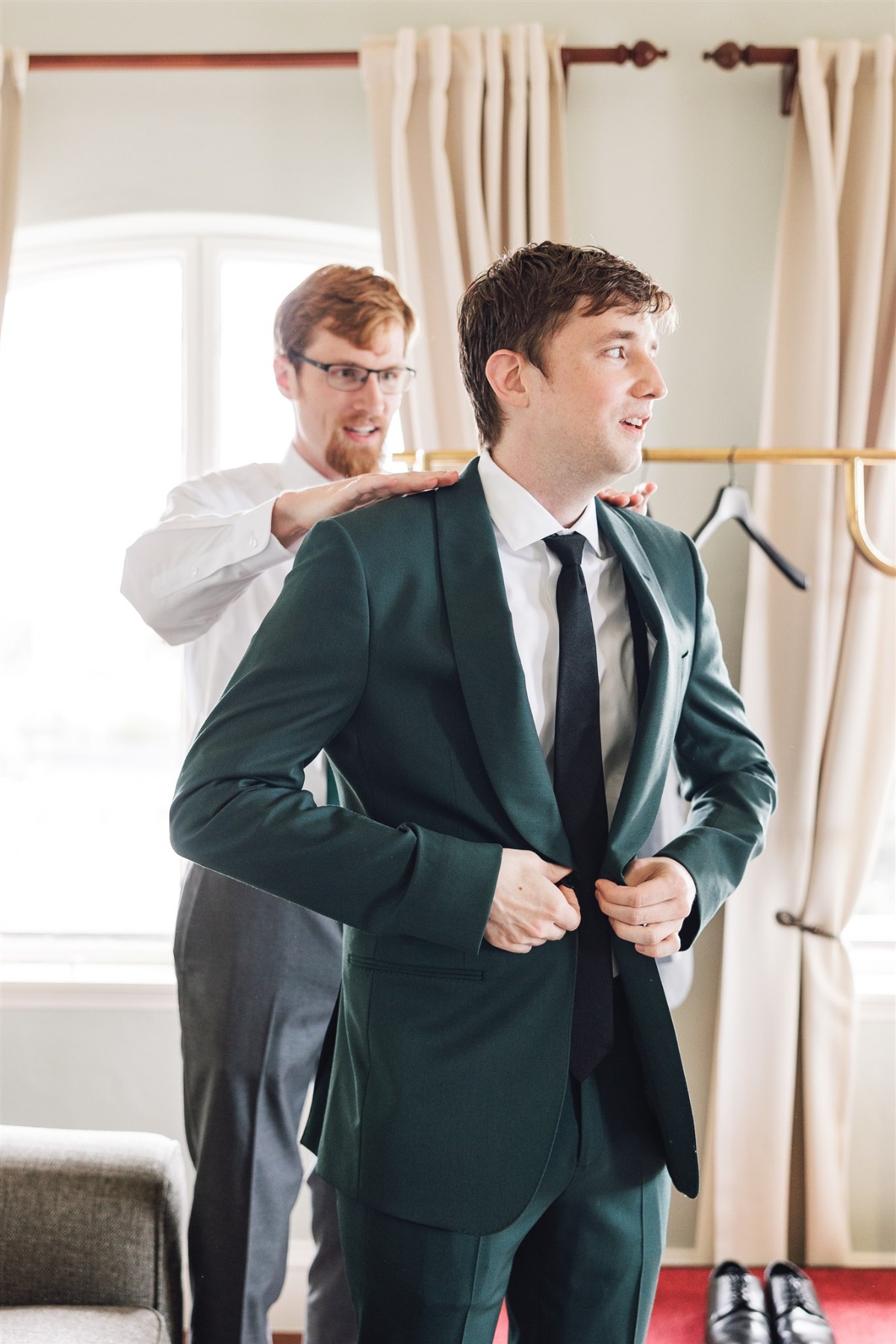 groom getting dressed in green suit