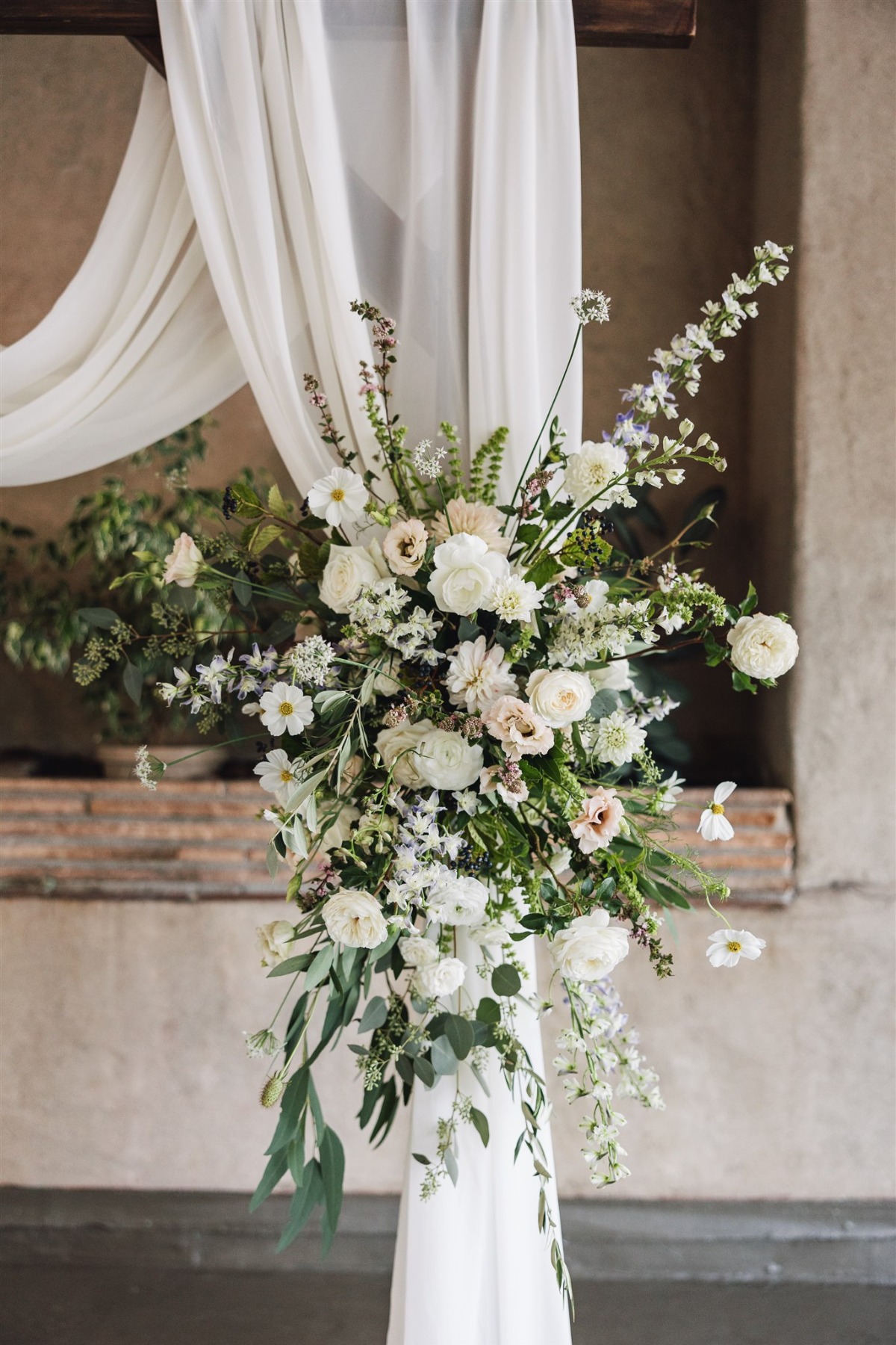 white fabric draped wedding ceremony arch