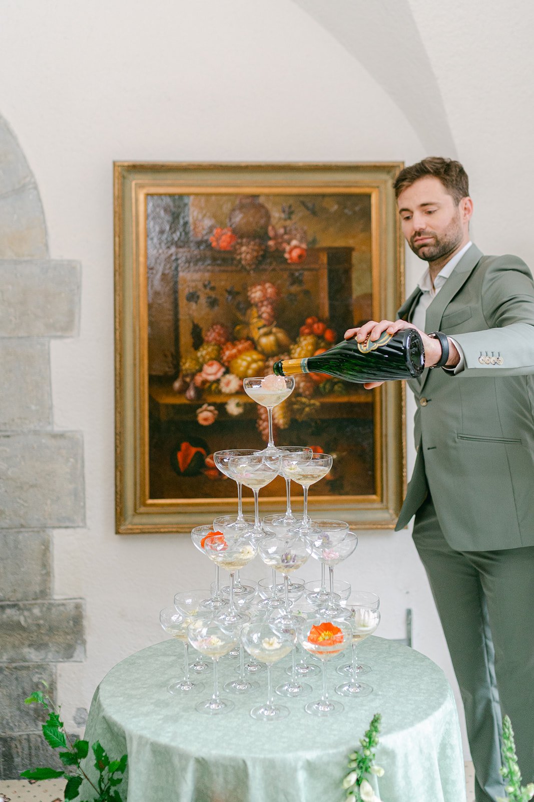 groom in sage suit with champagne tower