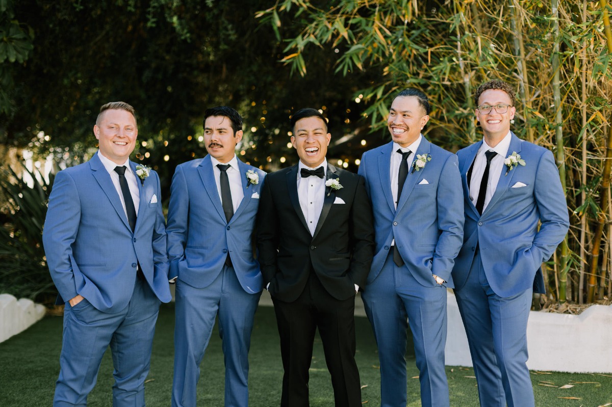 groom in black tux with groomsmen in blue suits